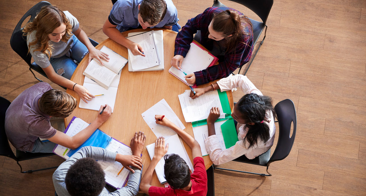 Overhead Shot Of High School Pupils In Group Study Around Tables